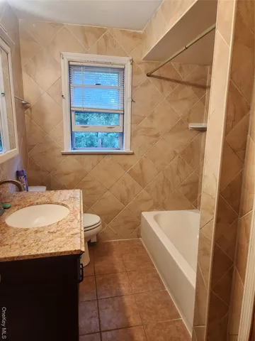 a bathroom with a granite countertop sink a toilet and bathtub