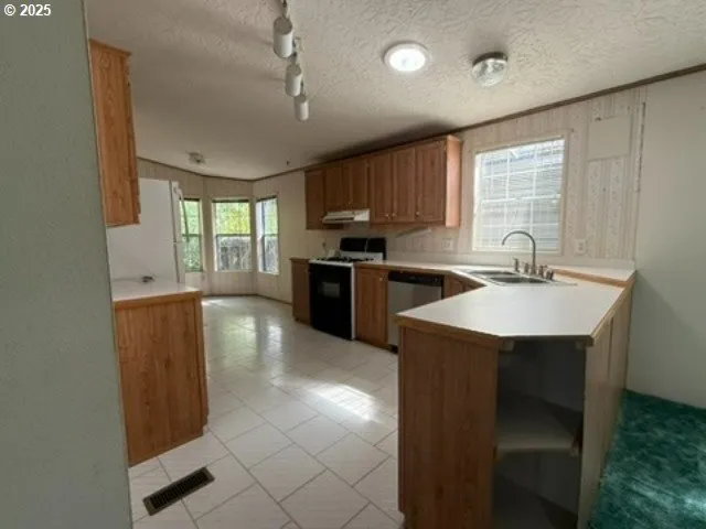 a kitchen with stainless steel appliances granite countertop a sink a stove and a refrigerator