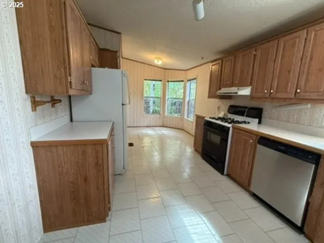 a kitchen with stainless steel appliances granite countertop a stove a refrigerator and a sink with wooden cabinets
