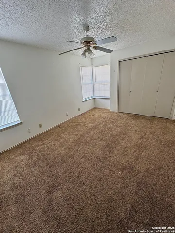 an empty room with a ceiling fan and window