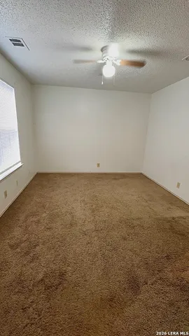 an empty room with a fan & a window