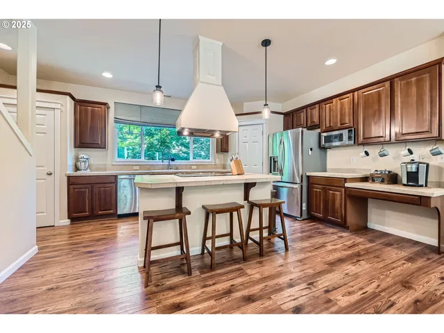 a living room with stainless steel appliances kitchen island granite countertop furniture wooden floor and a kitchen view