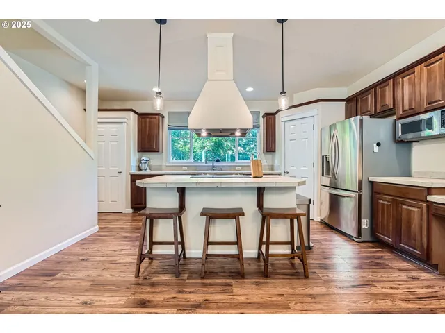 a kitchen with stainless steel appliances granite countertop a refrigerator a stove and a wooden floors