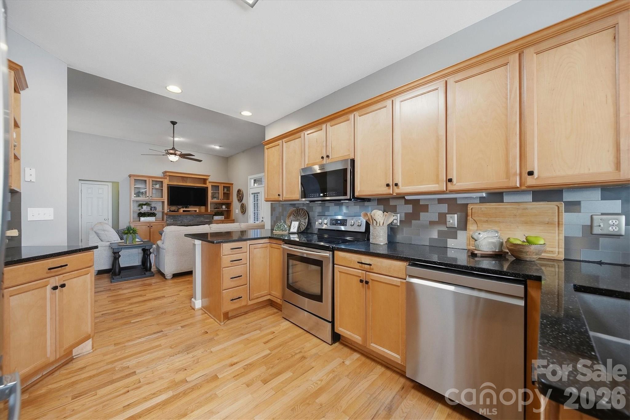2555 Knox Landing Road Connelly Springs, NC 28612 - Photo 15 of 48 a kitchen with stainless steel appliances granite countertop a stove top oven a sink dishwasher and a refrigerator with wooden floor