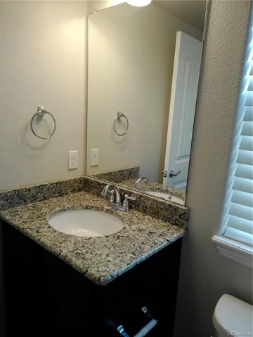a bathroom with a granite countertop sink and a mirror