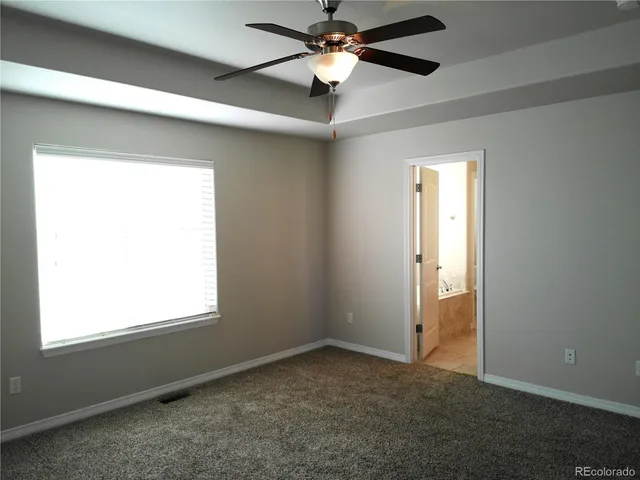 an empty room with a window and a fan