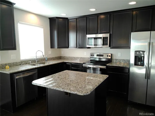 a kitchen with a sink a microwave a stove and refrigerator