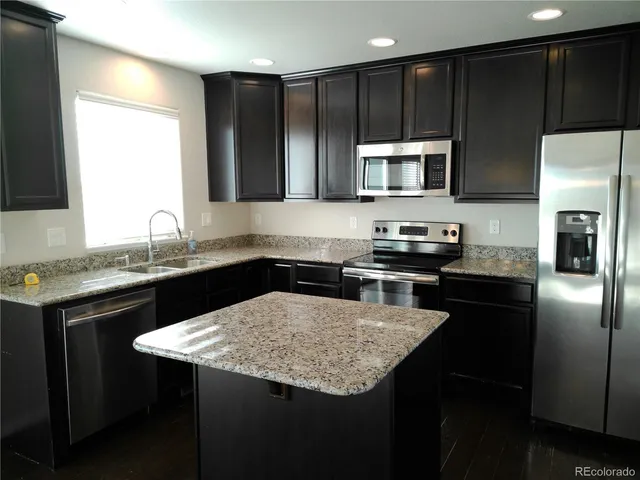 a kitchen with a sink a microwave a stove and refrigerator