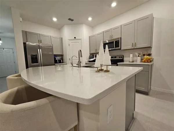 a kitchen with stainless steel appliances a sink a stove a refrigerator with white cabinets