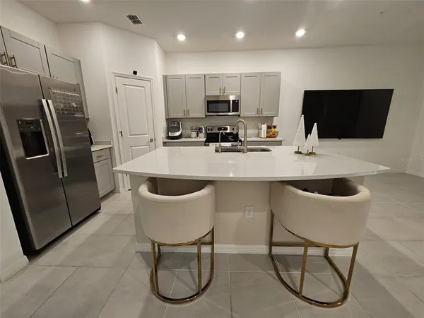 a kitchen with stainless steel appliances granite countertop a table chairs sink refrigerator and microwave