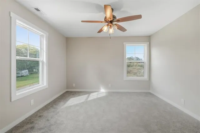 an empty room with windows and fan