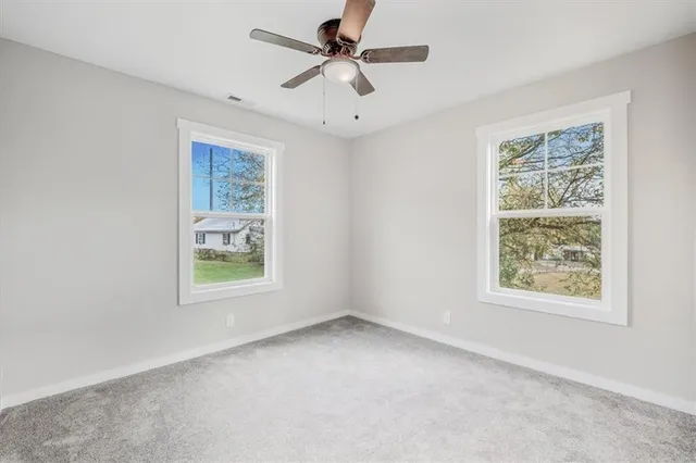 an empty room with windows and ceiling fan