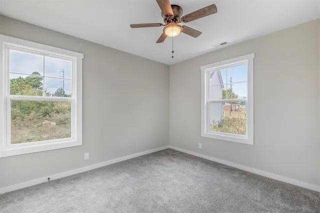 an empty room with windows and ceiling fan