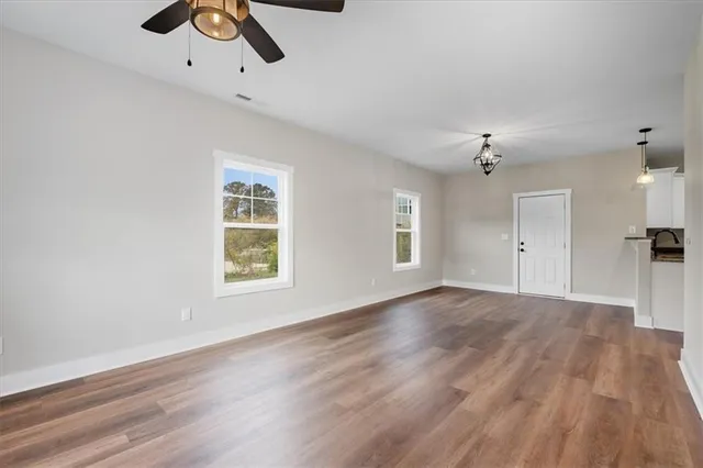 a view of an empty room with wooden floor and a window