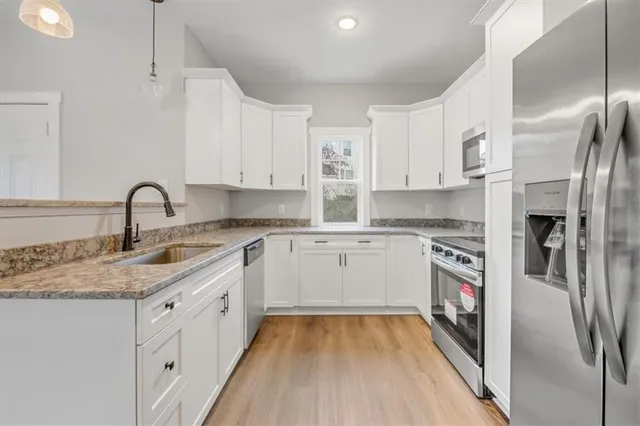 a kitchen with stainless steel appliances granite countertop a refrigerator sink and white cabinets