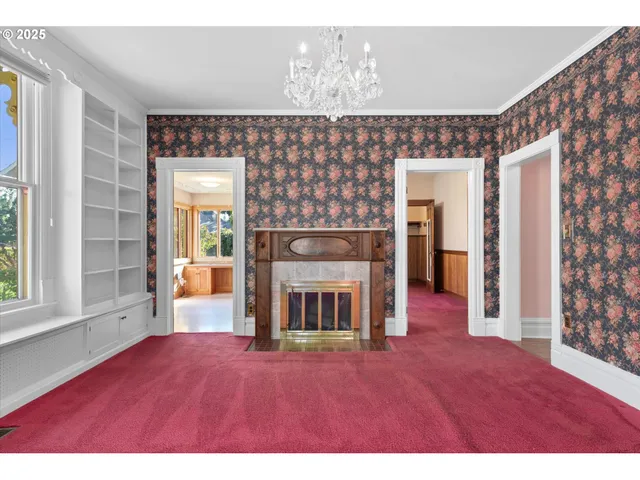 a view of an empty room with wooden floor and a large window