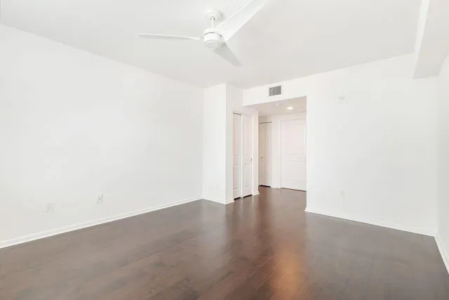 an empty room with wooden floor and ceiling fan