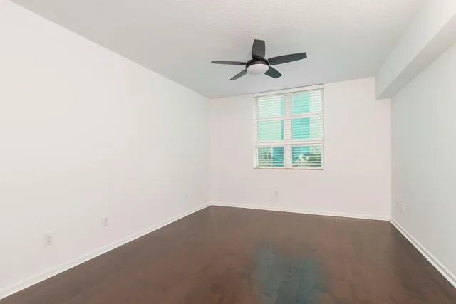 an empty room with a window and a ceiling fan