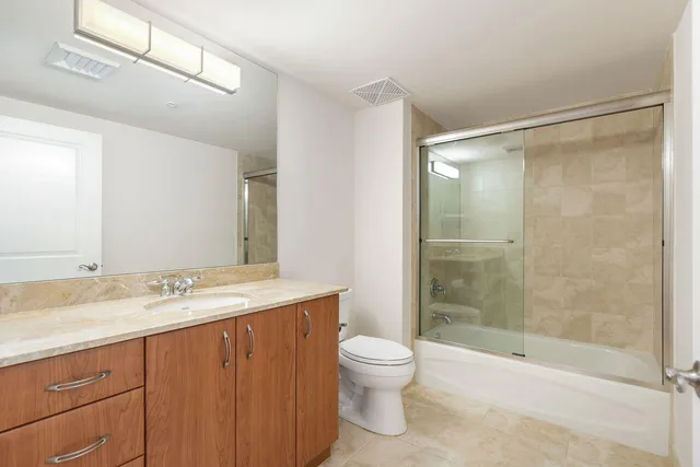 a bathroom with a granite countertop sink toilet and shower