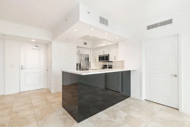 a large white kitchen with kitchen island a sink a stove and refrigerator