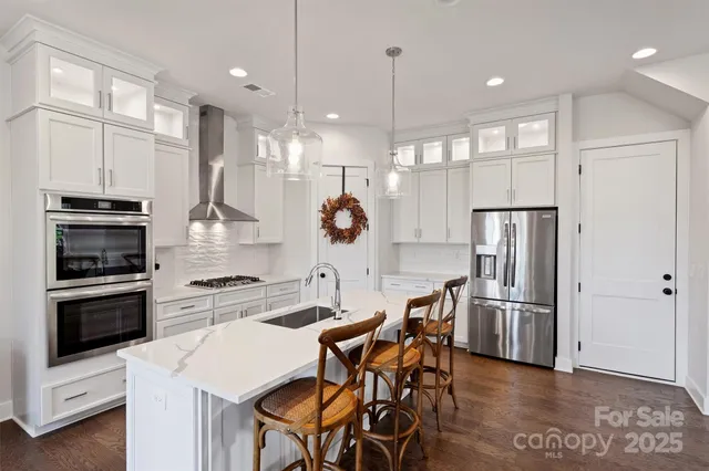 a kitchen with stainless steel appliances kitchen island granite countertop a refrigerator a stove a kitchen island with a dining table and chairs