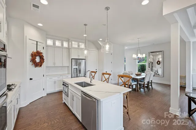 a kitchen with kitchen island a sink a stove a dining table and chairs