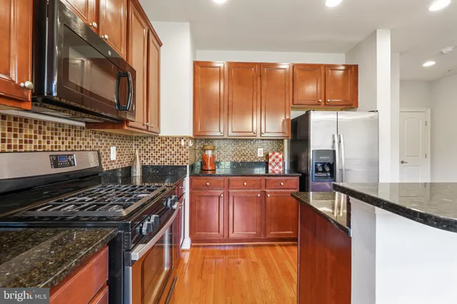 a kitchen with stainless steel appliances granite countertop a stove top oven a refrigerator a sink and dishwasher