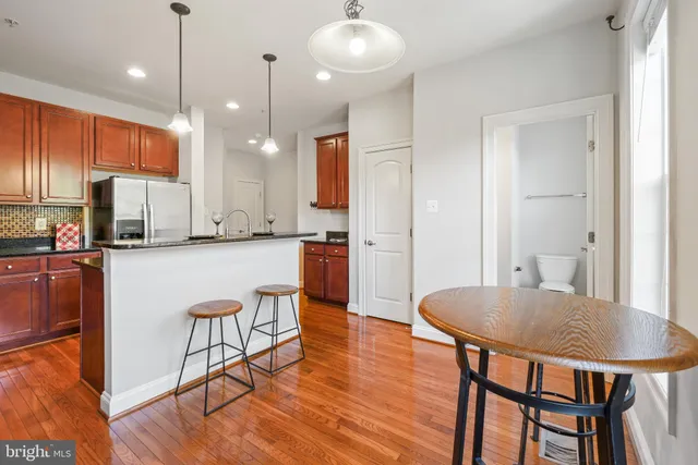 a kitchen with stainless steel appliances kitchen island granite countertop a dining table chairs and white cabinets next to a window