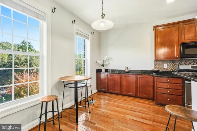 a kitchen with stainless steel appliances granite countertop a stove a sink a dining table and chairs with wooden floor