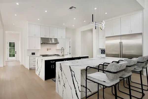 a kitchen with kitchen island granite countertop a stove a sink a refrigerator and chairs