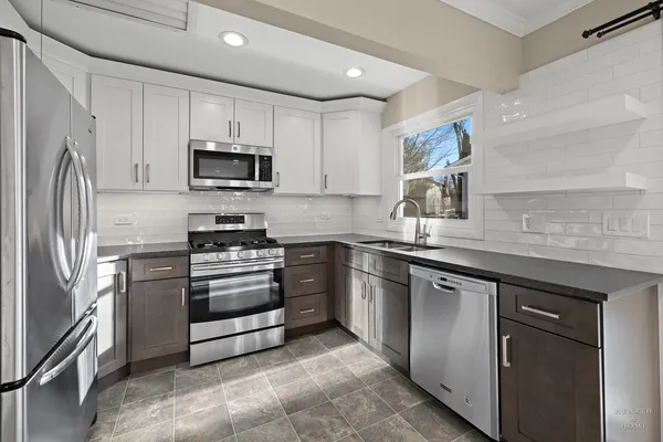 a kitchen with granite countertop a refrigerator stove and microwave