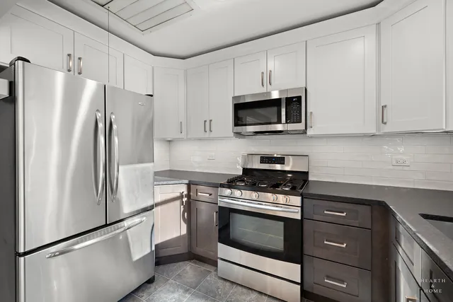 a kitchen with granite countertop white cabinets and stainless steel appliances
