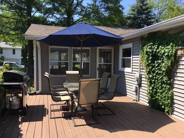 a patio with wooden floor table and chairs