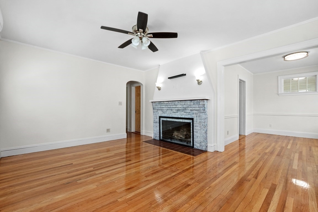 129 Virginia Road Waltham, MA 02453 - Photo 8 of 27 a view of a livingroom with wooden floor a ceiling fan and a fireplace