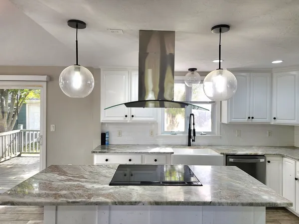 a kitchen with kitchen island granite countertop a sink a counter space and cabinets