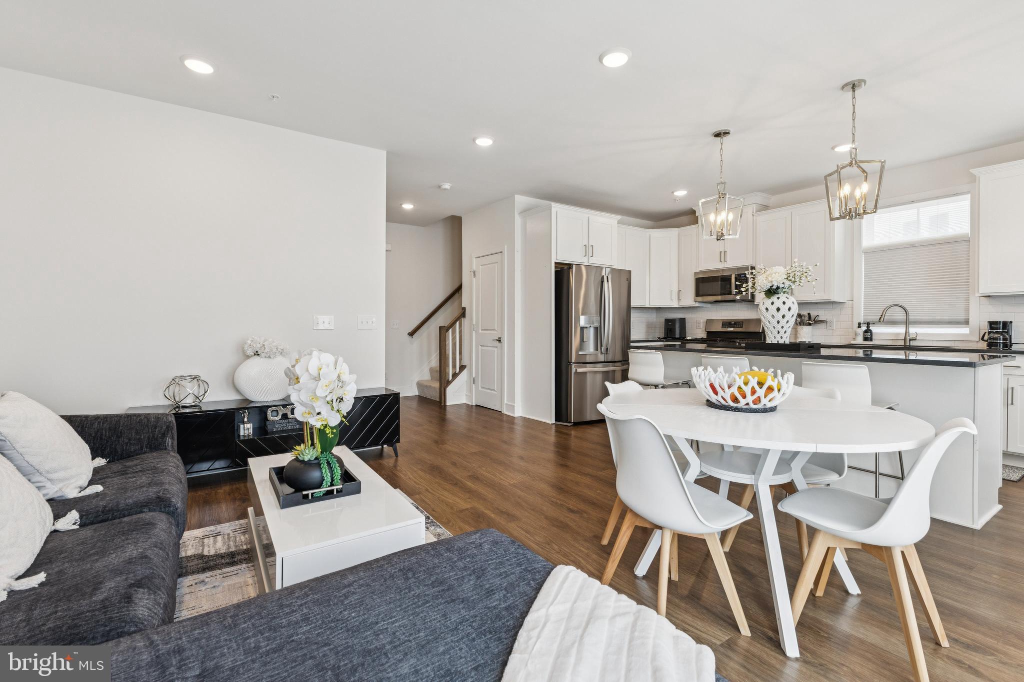 42597 Nubbins Terrace Ashburn, VA 20147 - Photo 12 of 40 a kitchen with stainless steel appliances kitchen island granite countertop a dining table chairs refrigerator and sink