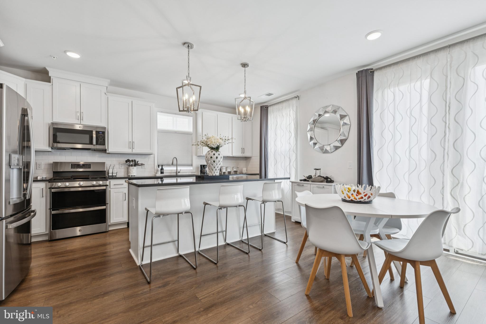 42597 Nubbins Terrace Ashburn, VA 20147 - Photo 14 of 40 a kitchen with stainless steel appliances kitchen island granite countertop a dining table chairs and a refrigerator