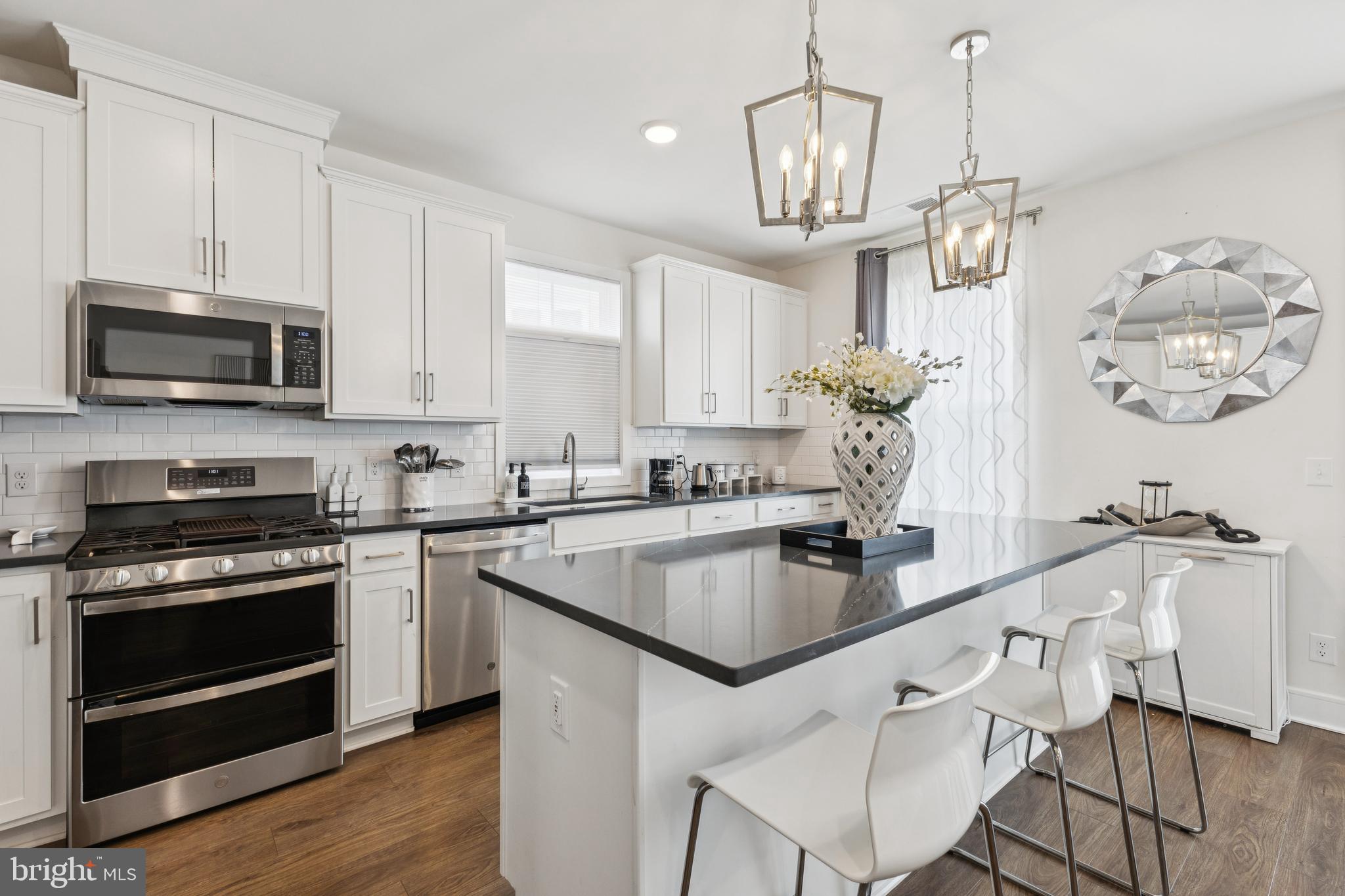 42597 Nubbins Terrace Ashburn, VA 20147 - Photo 15 of 40 a kitchen with kitchen island granite countertop a sink cabinets and stainless steel appliances