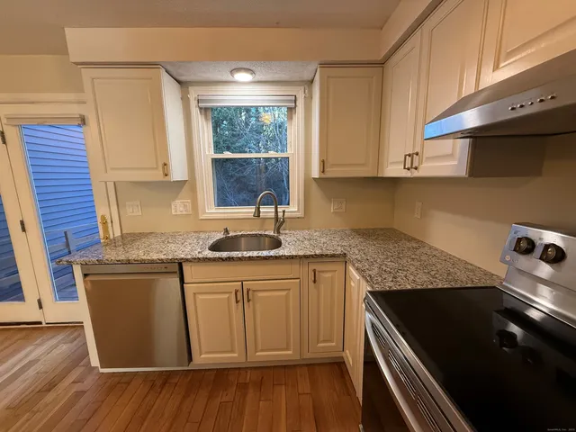 a kitchen with granite countertop a sink a stove and cabinets