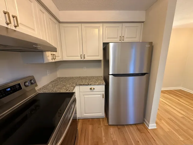 a kitchen with a refrigerator a stove and wooden floor