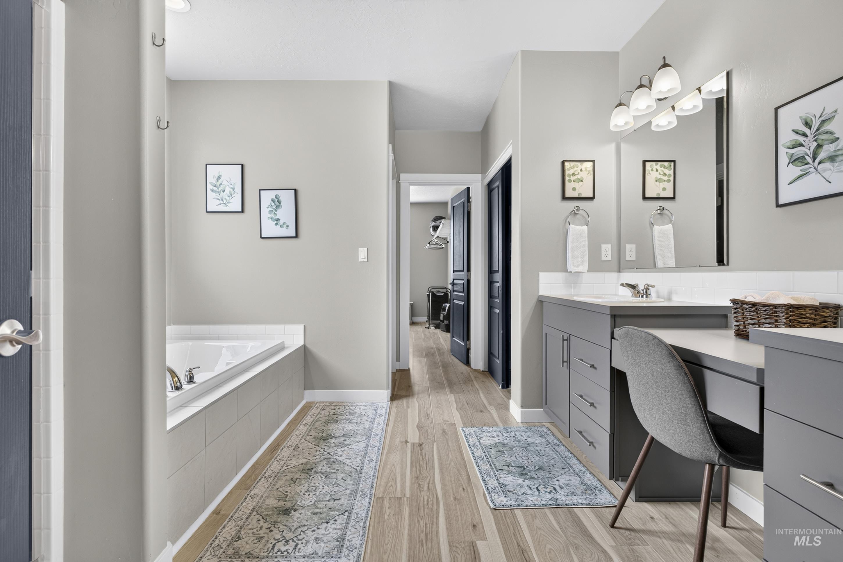 132 Mores Creek Rim Road Boise, ID 83716 - Photo 20 of 44 Soaking tub with tiled surround, dual vanity with undermount sinks, wood-finish flooring, and a dedicated vanity counter