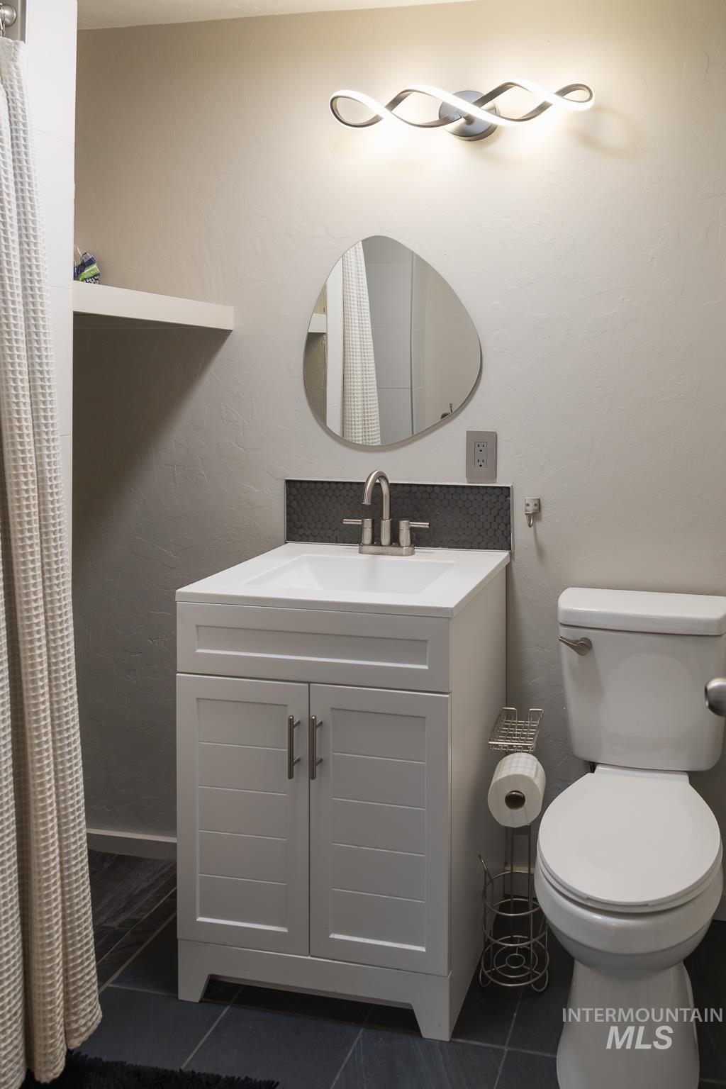 661 Southwest 3rd Street Ontario, OR 97914 - Photo 21 of 45 Full bathroom featuring vanity, dark tile patterned floors, and a textured wall
