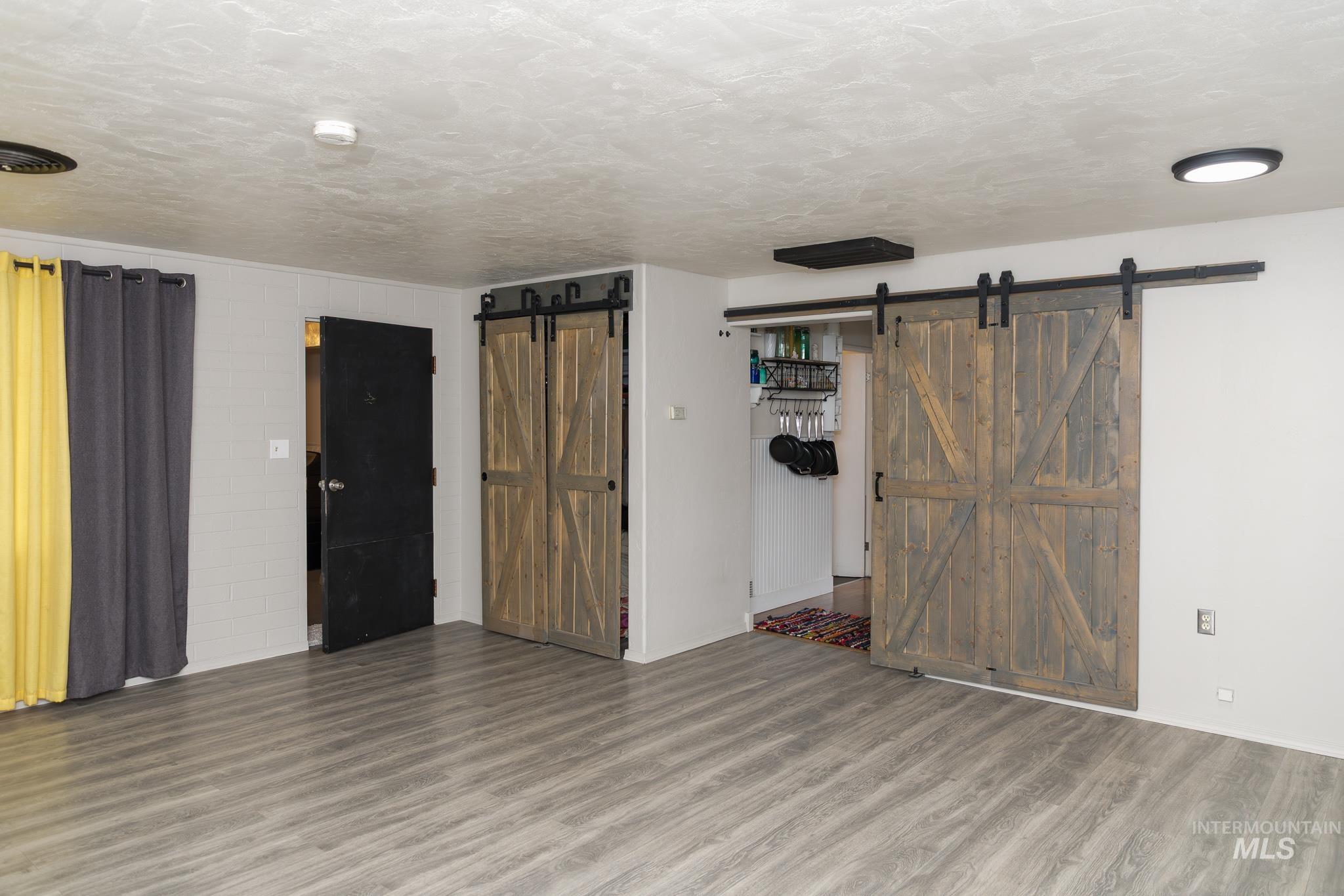 661 Southwest 3rd Street Ontario, OR 97914 - Photo 25 of 45 Unfurnished living room with a barn door, wood finished floors, and a textured ceiling