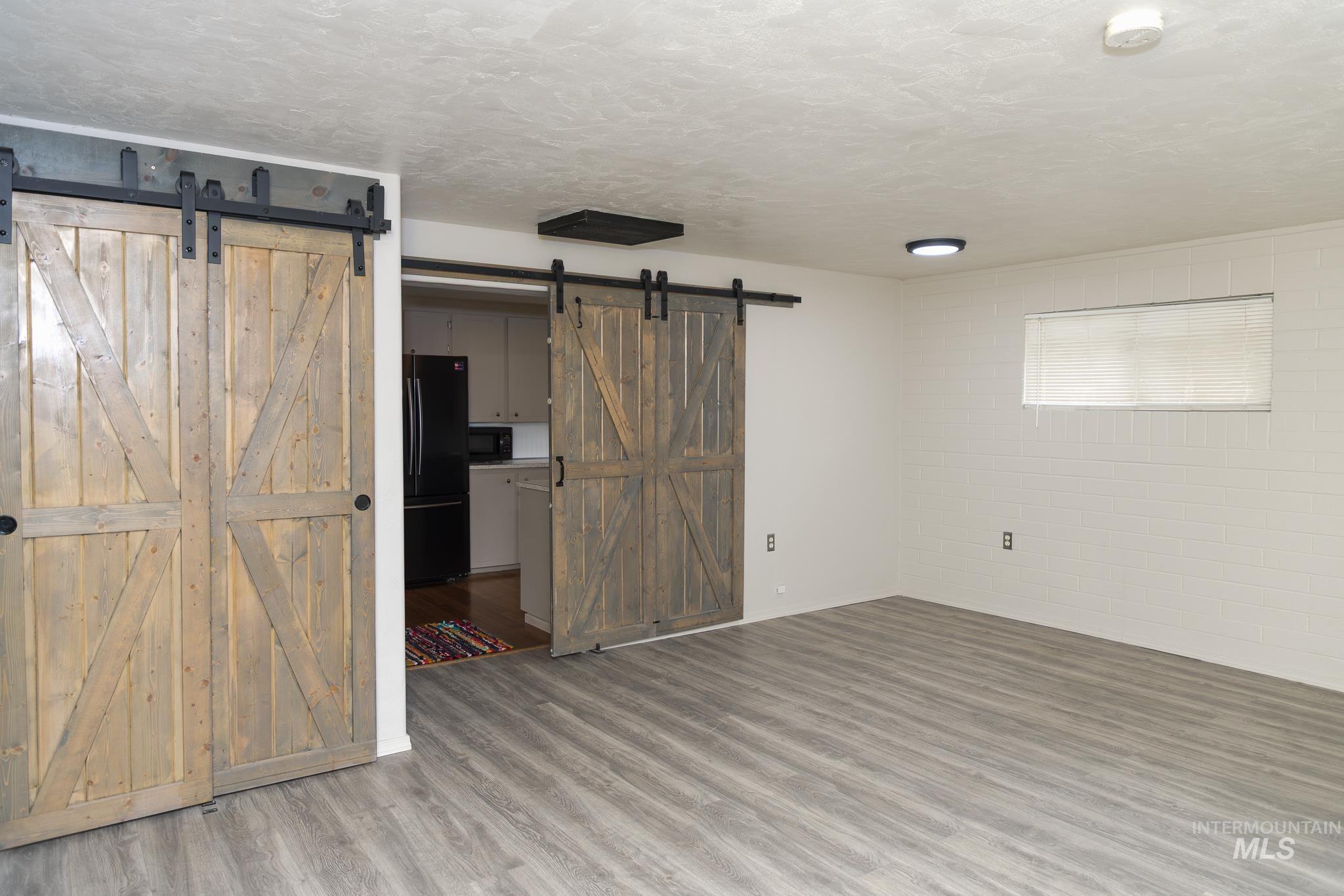 661 Southwest 3rd Street Ontario, OR 97914 - Photo 26 of 45 Spare room featuring a barn door, a textured ceiling, wood finished floors, and concrete block wall