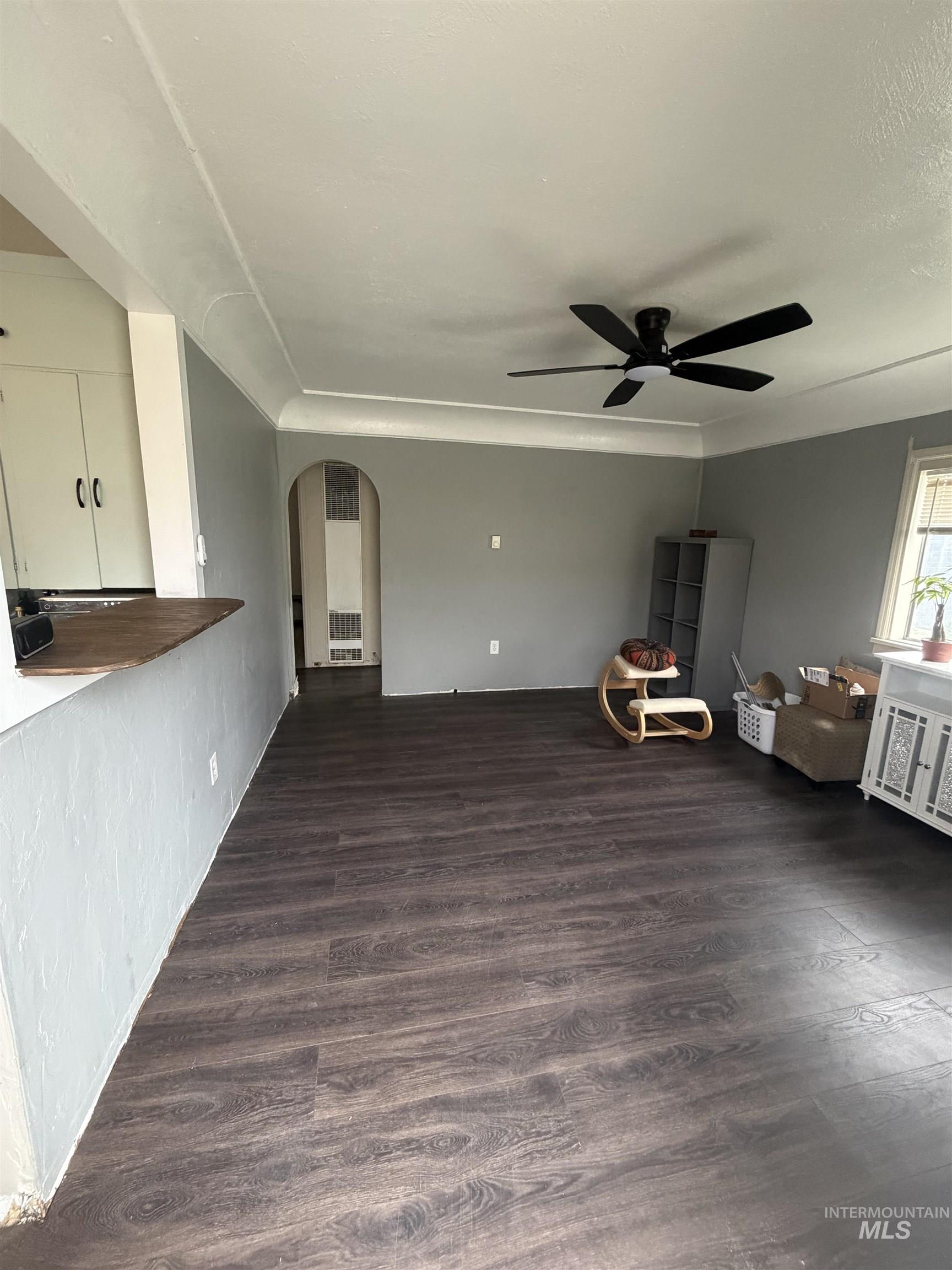 661 Southwest 3rd Street Ontario, OR 97914 - Photo 33 of 45 Unfurnished living room with arched walkways, dark wood finished floors, and a ceiling fan
