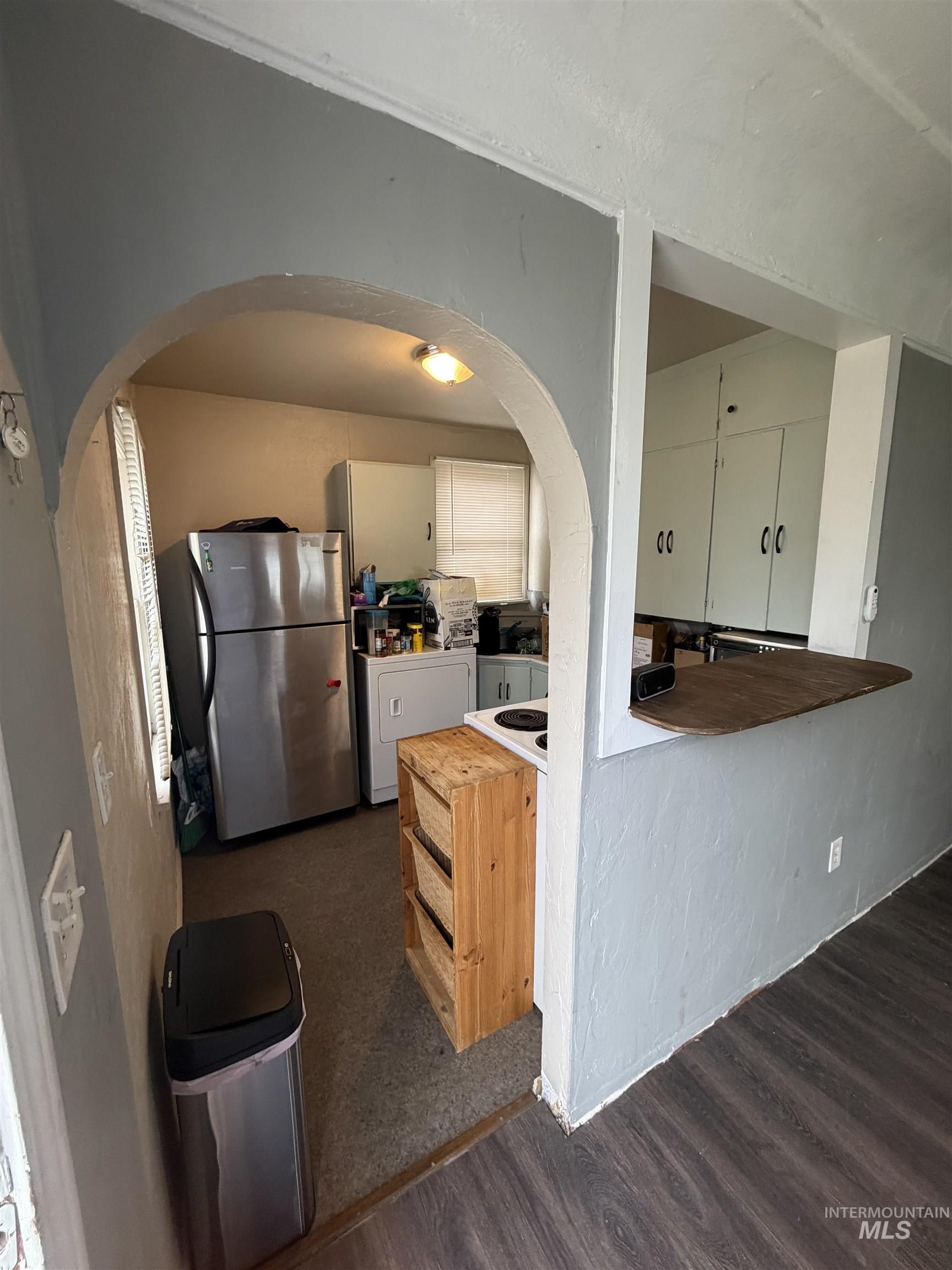 661 Southwest 3rd Street Ontario, OR 97914 - Photo 35 of 45 Kitchen with freestanding refrigerator, white cabinetry, washer / dryer, arched walkways, and dark wood-style floors