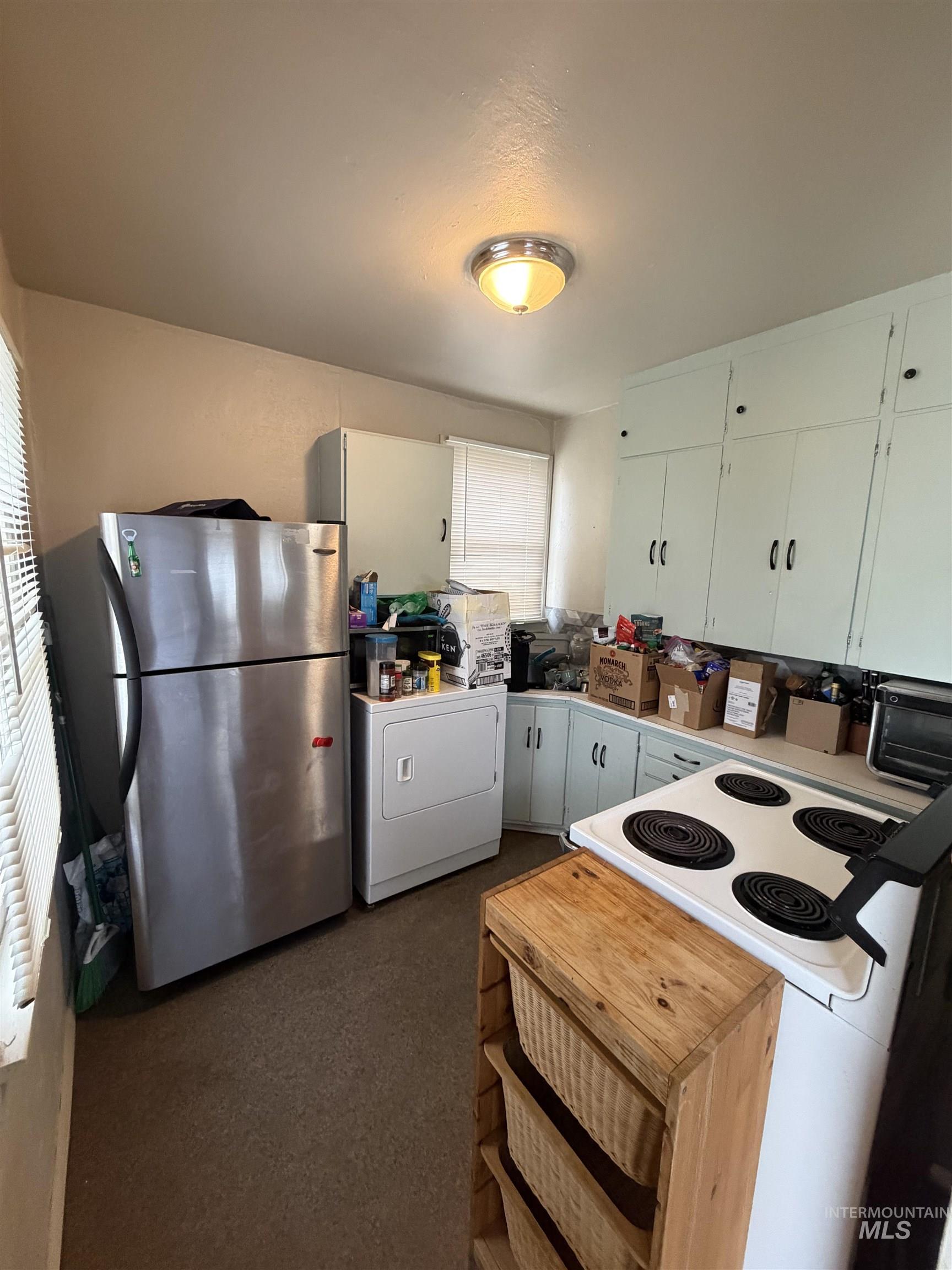 661 Southwest 3rd Street Ontario, OR 97914 - Photo 37 of 45 Kitchen featuring white electric stove, freestanding refrigerator, light countertops, washer / clothes dryer, and white cabinetry