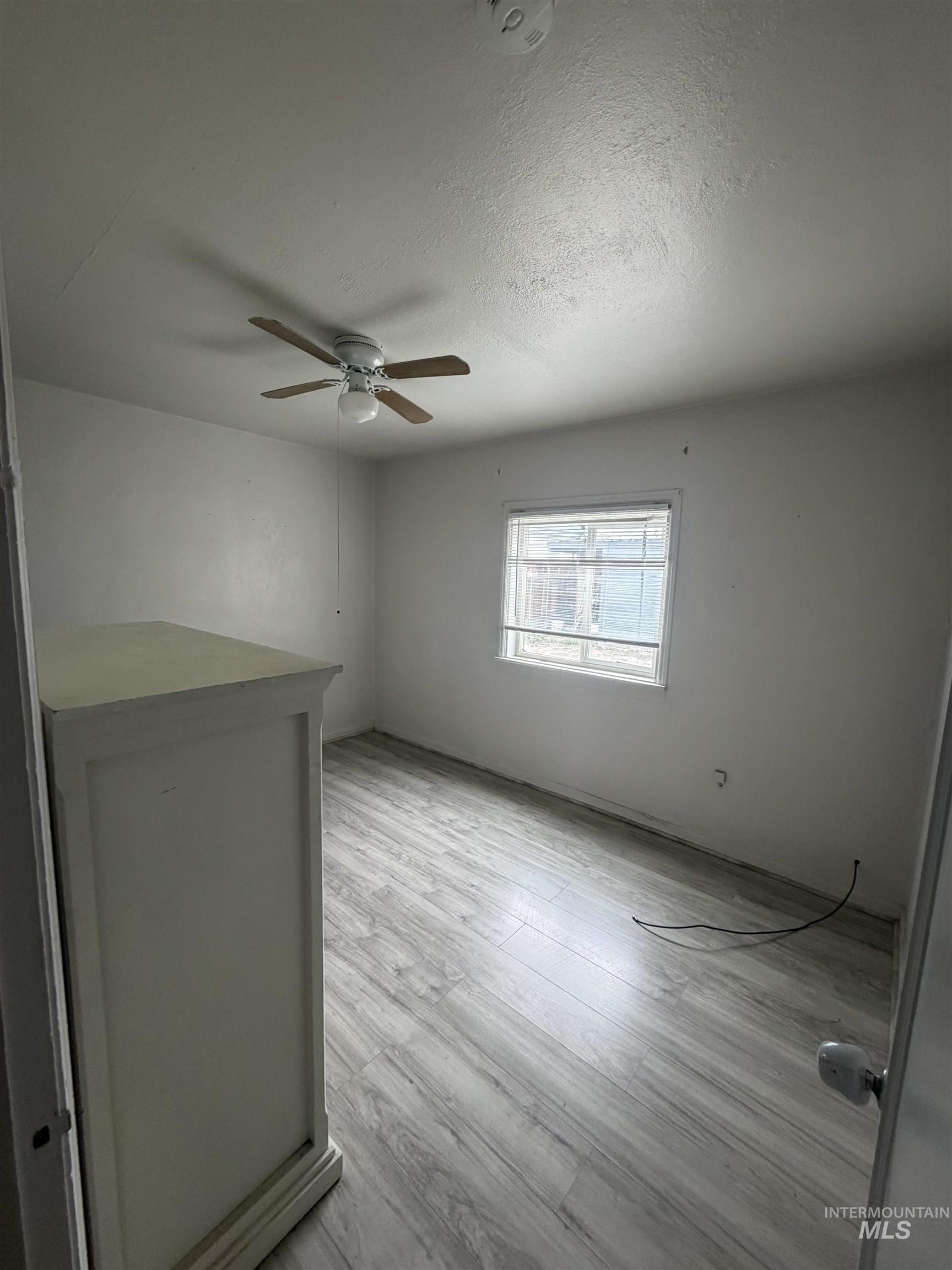 661 Southwest 3rd Street Ontario, OR 97914 - Photo 38 of 45 Empty room with a textured ceiling, light wood-style floors, and ceiling fan