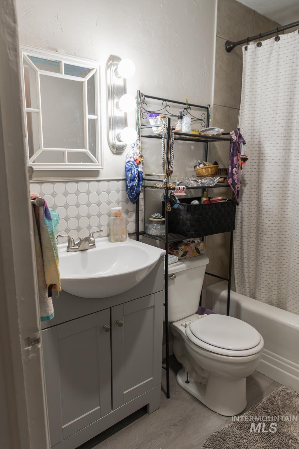 661 Southwest 3rd Street Ontario, OR 97914 - Photo 8 of 45 Full bathroom with vanity, shower / tub combo with curtain, backsplash, and light wood-type flooring