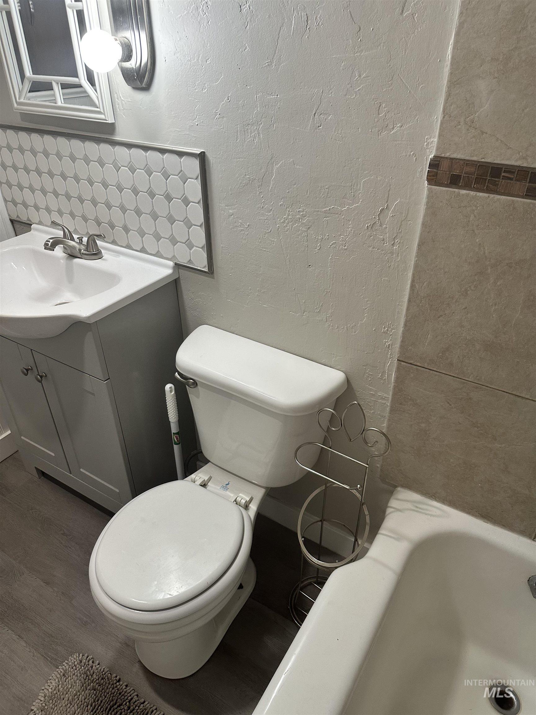 661 Southwest 3rd Street Ontario, OR 97914 - Photo 9 of 45 Bathroom with a textured wall, vanity, a bath, and dark wood-style flooring